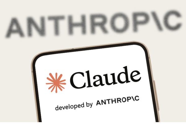 Anthropic on screen behind smartphone display of Claude with logo