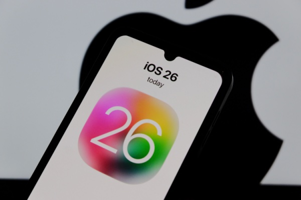 Apple iPhone with iOS 26 on screen in front of silhouette apple logo