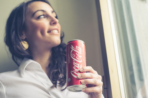 Young woman smiles while holding can of coca-cola