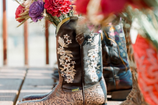 Floral print cowboy boots holding dried flowers on display