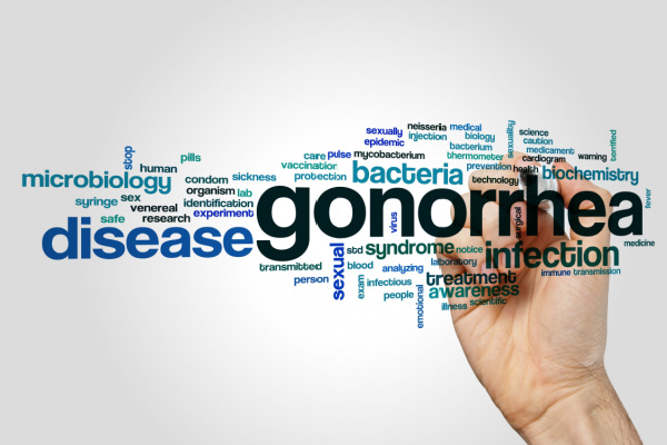 Hand behind plexiglass writing words like gonorrhea and disease