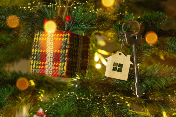 Miniature home with large key hang on Christmas Tree next to a gift ornament