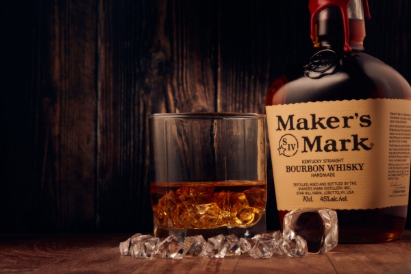 Bottle of Maker's Mark Bourbon Whisky next to glass of whisky on the rocks