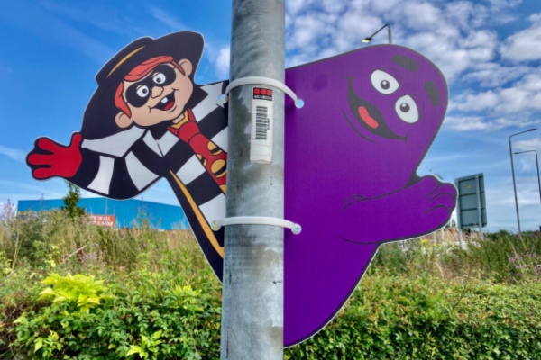 Large Hamburgler and Grimace Cut Outs attached to a light pole