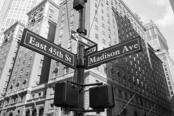 Black and white image of Easte 45th St and Madison Ave street signs and high rises in NYC
