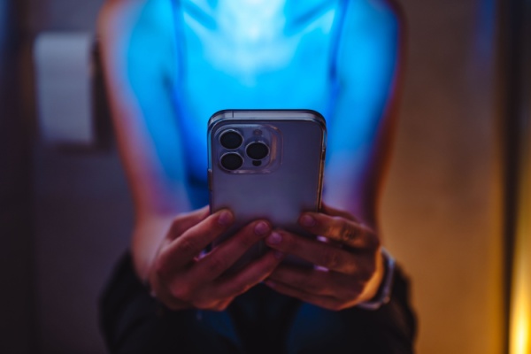 Woman sitting on toilet scrolling on her phone