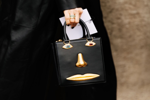 Woman han holding anatomy jewelry Schiaparelli bag in Paris street style 2024