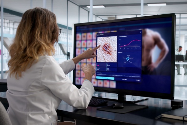 Female doctor in lab using computer to analyze skin growth to see if it's skin cancer