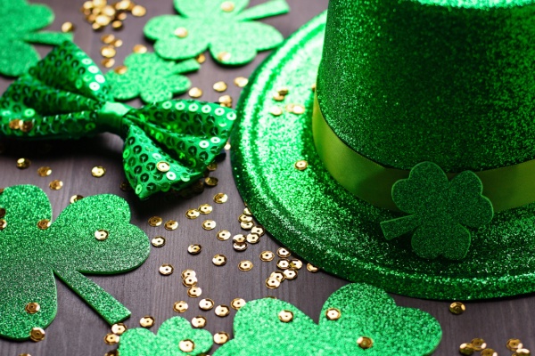 St. Patrick's Day green hat, paper green clovers, green sequined bow and gold confetti on table
