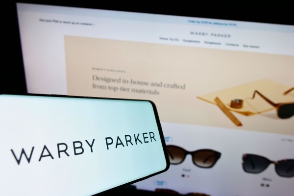 Warby Parker logo in front of their eyewear website with sunglasses