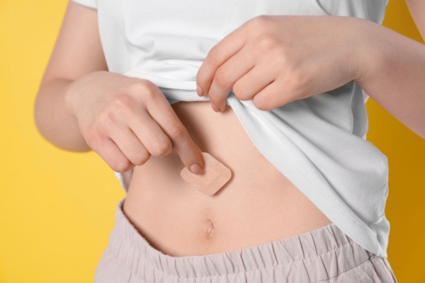 Woman applying estrogen patch to belly